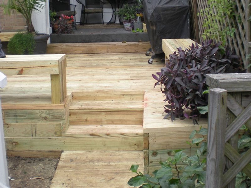 new wood deck with stairs leading up to a backyard patio