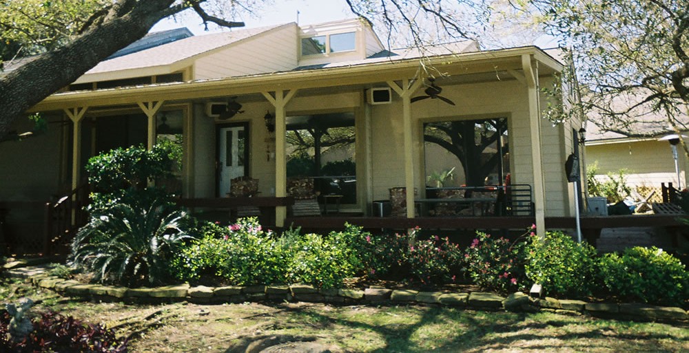 wood porch addition with posts and railing beside a Houston area home